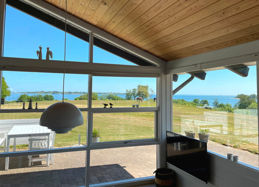 Heller Wohn-/Essbereich im skandinavischen Design mit bodentiefen Fenstern; familienfreundliche Ferienunterkunft an der Ostsee.