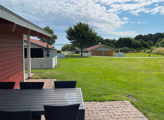 Heller Wohn-/Essbereich im skandinavischen Design mit bodentiefen Fenstern; familienfreundliche Ferienunterkunft an der Ostsee.