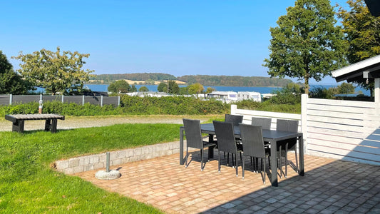 Heller Wohn-/Essbereich im skandinavischen Design mit großer Fensterfront; familienfreundliche Ferienunterkunft an der Ostsee.